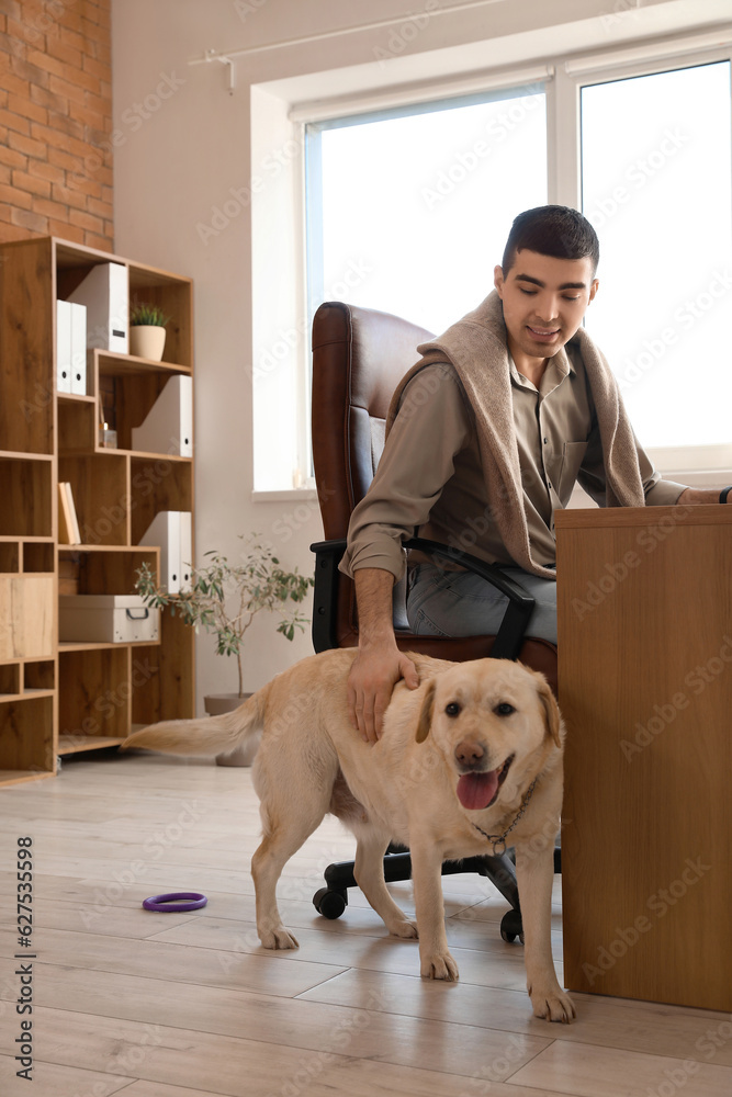 Young man with cute Labrador dog in office