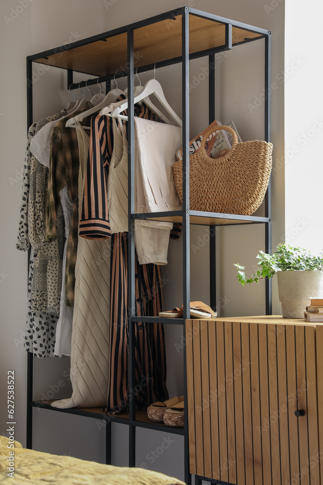 Shelving unit with clothes, shoes and bag in light bedroom