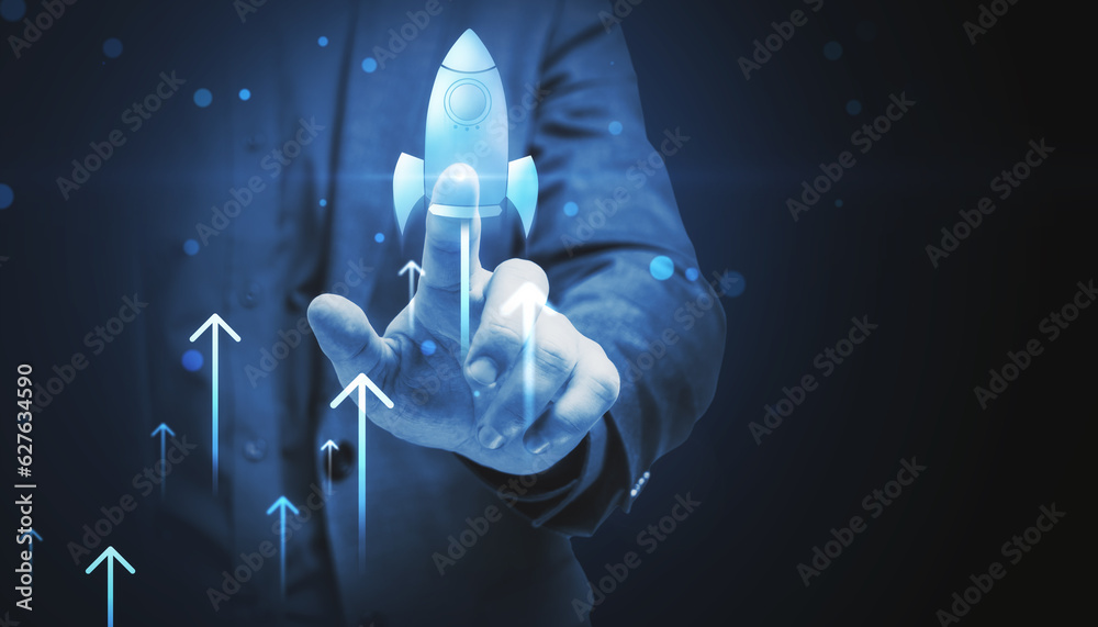 Close up of businessman hand pointing at glowing flying blue rocket on dark background with mock up 