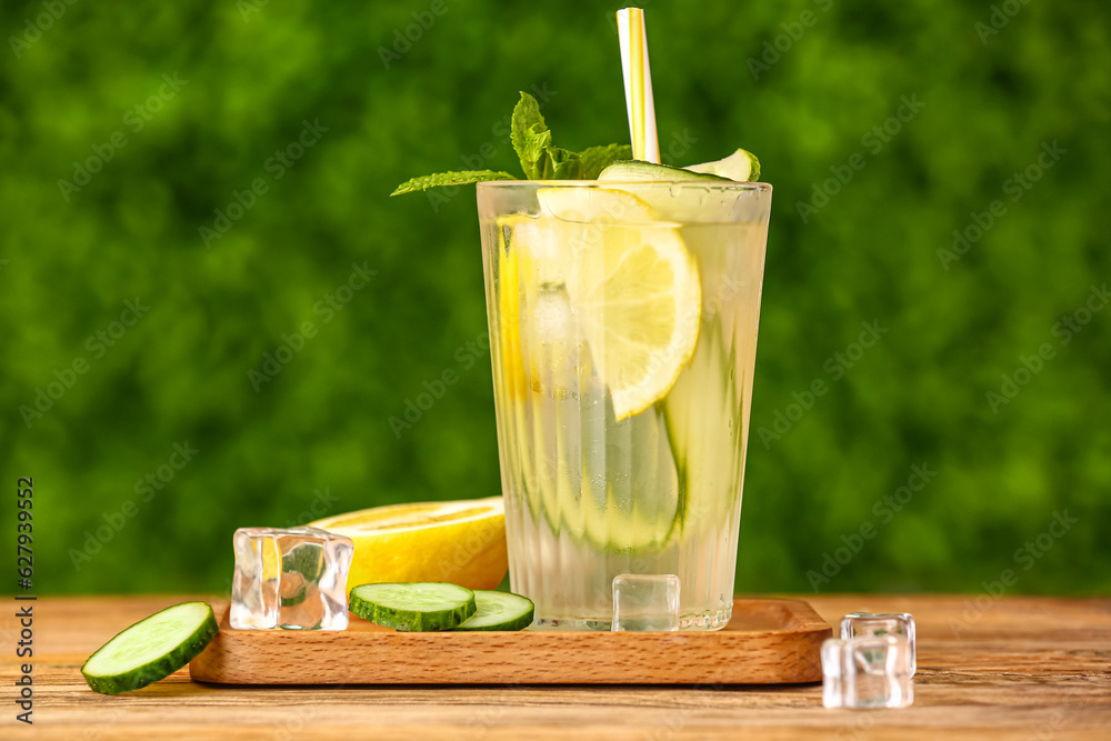 Glass of lemonade with cucumber and mint on wooden table outdoors