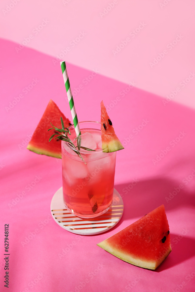 Glass of tasty watermelon cocktail on pink table near wall