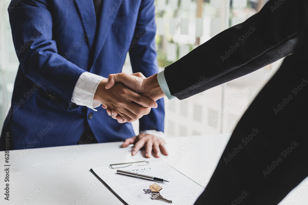 Businessman and real estate agent shaking hands after negotiating home purchase agreement.