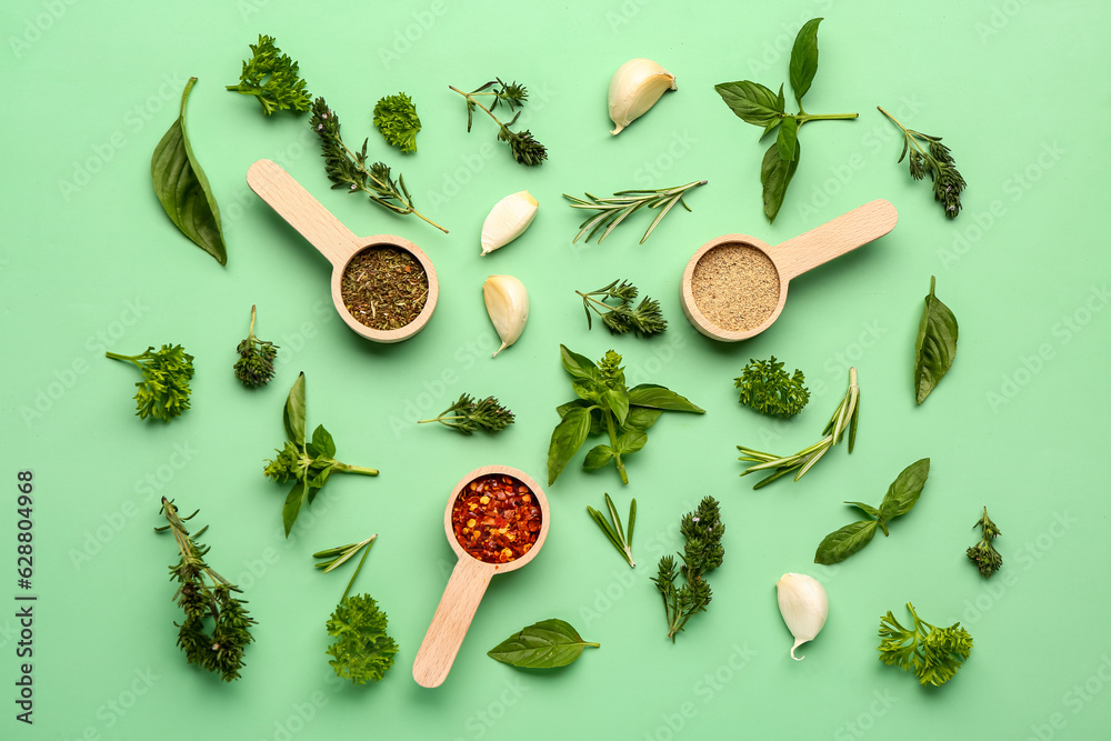 Composition with fresh herbs and scoops of spices on color background