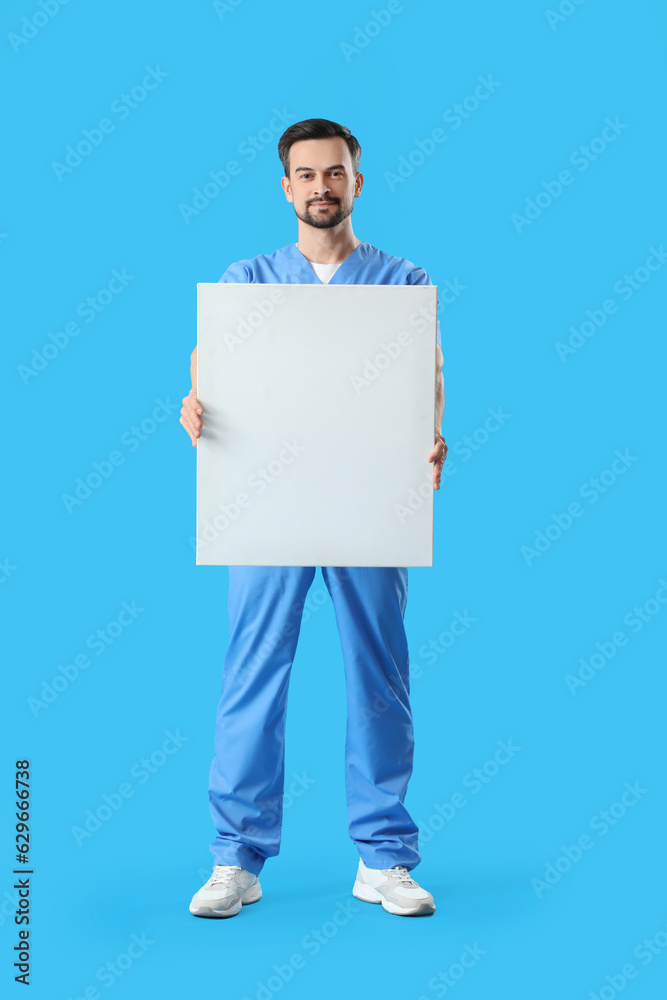 Male dentist with big plastic tooth on blue background