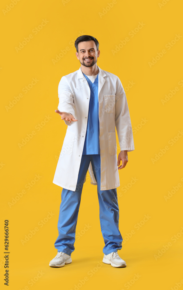Male dentist holding something on yellow background