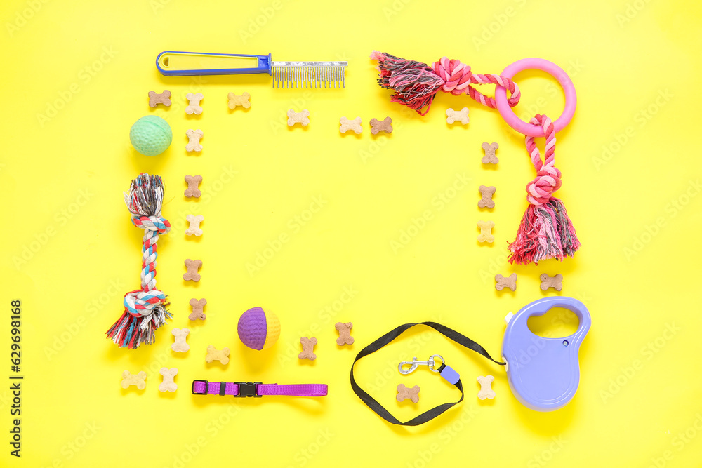 Frame made of pet care accessories and dry food on yellow background