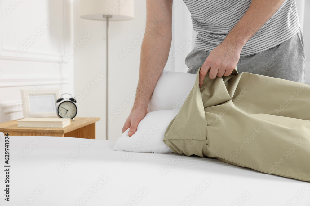 Man changing pillowcase at home, closeup. Domestic chores