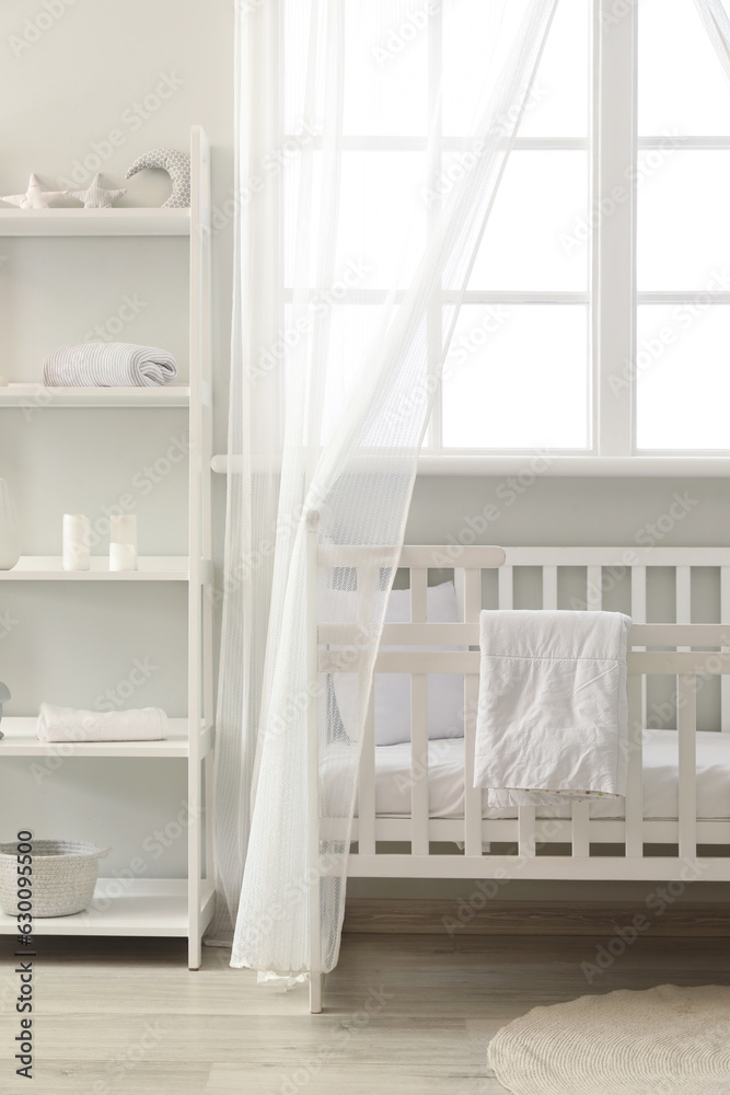 Interior of stylish childrens bedroom with crib and shelving unit