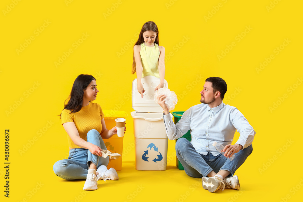 Family sorting garbage in recycle bins on yellow background