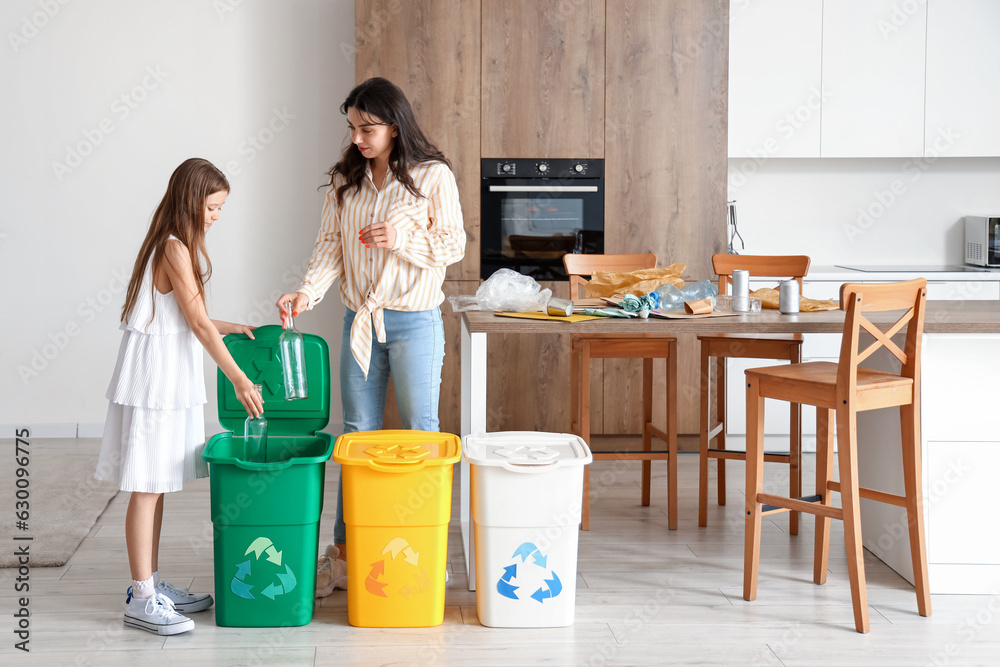 Little girl with her mother sorting glass garbage in kitchen