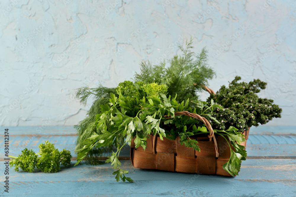 Basket with fresh herbs on color wooden table