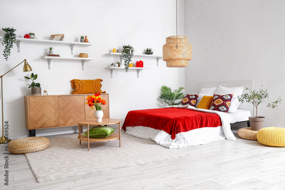 Interior of stylish bedroom with tulip flowers in vase on wooden table