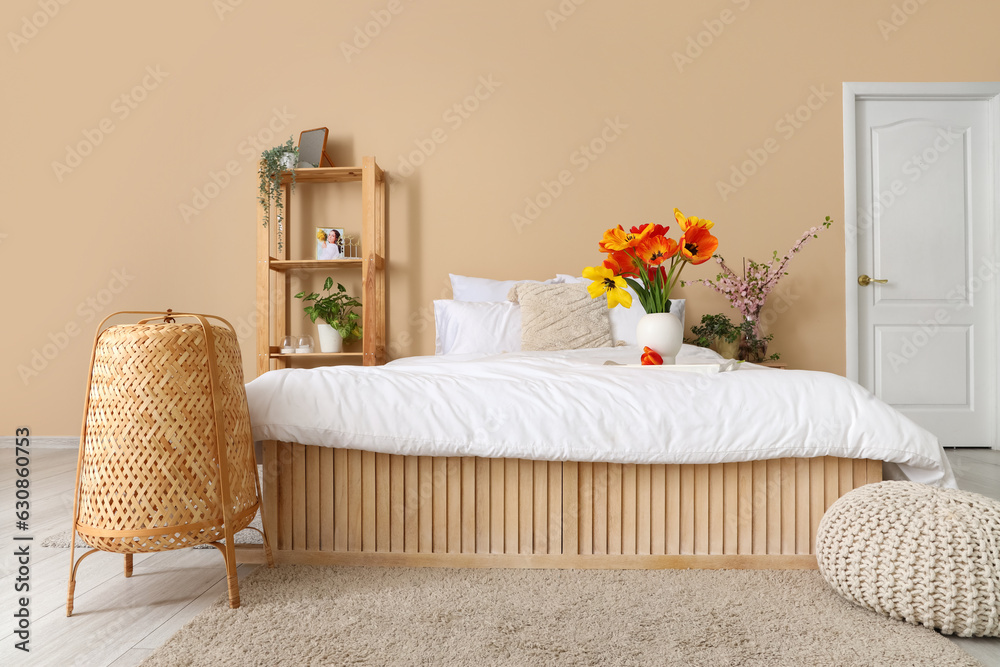 Interior of stylish living room with tulip flowers in vase on bed