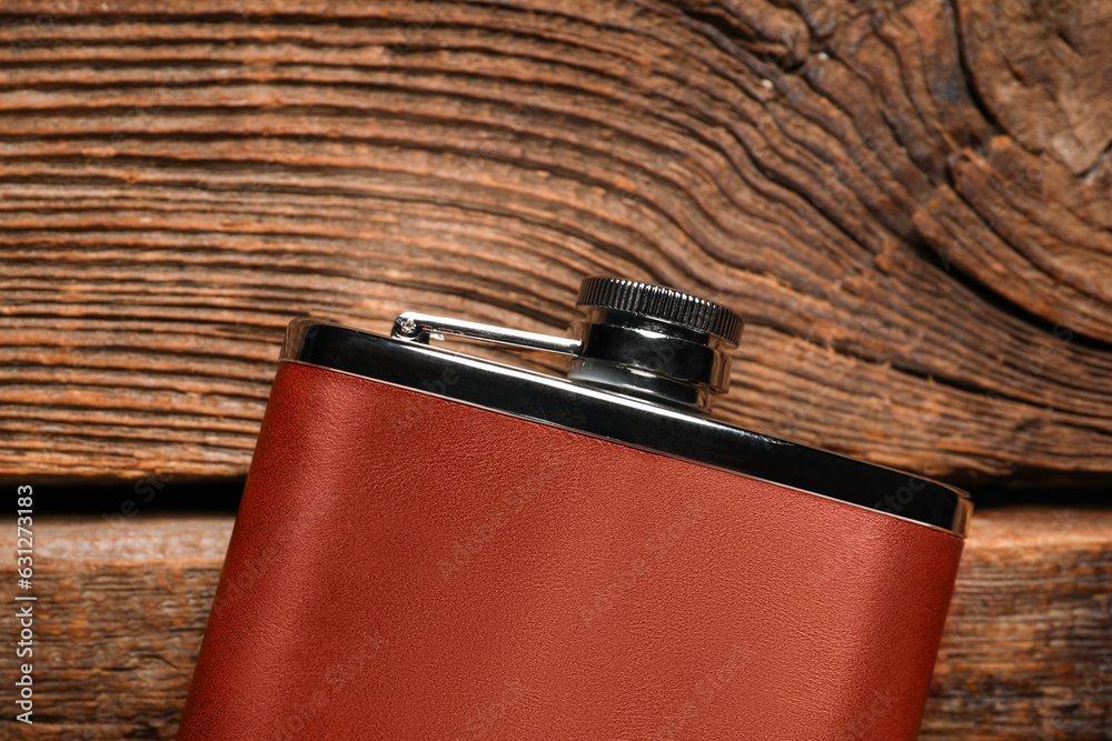 New hip flask on wooden background, closeup