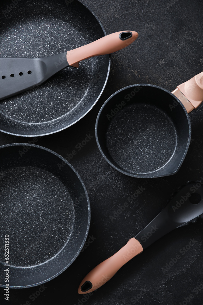 Cooking pots, frying pan and kitchen utensils on dark background