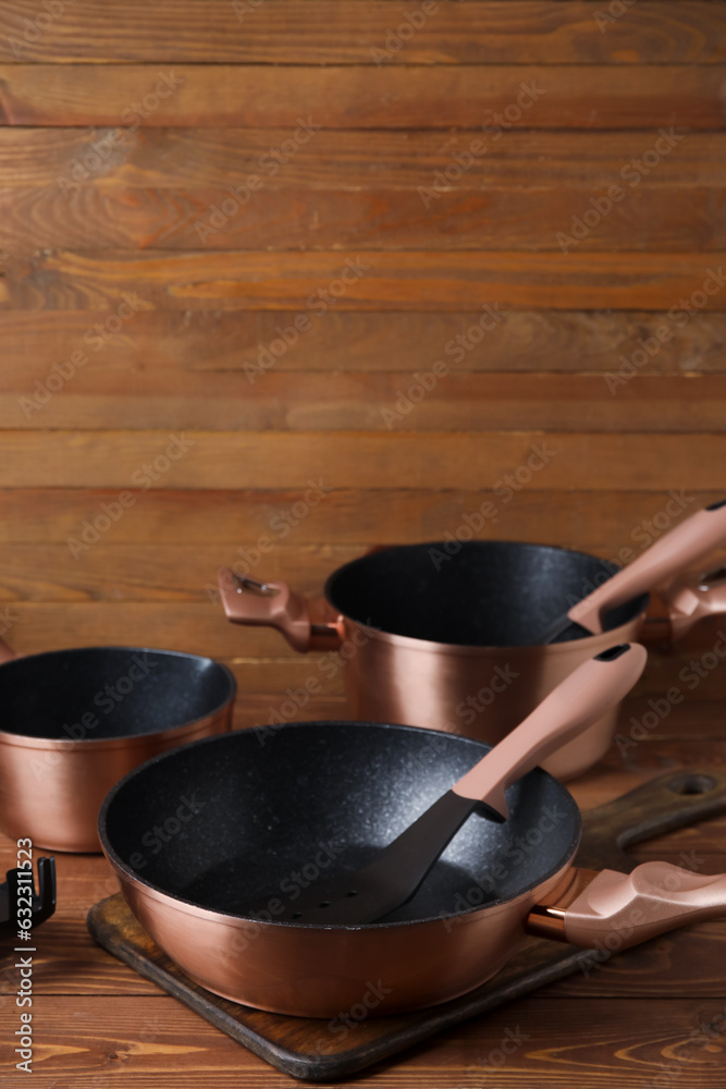 Set of copper cooking pots and kitchen utensils on wooden background