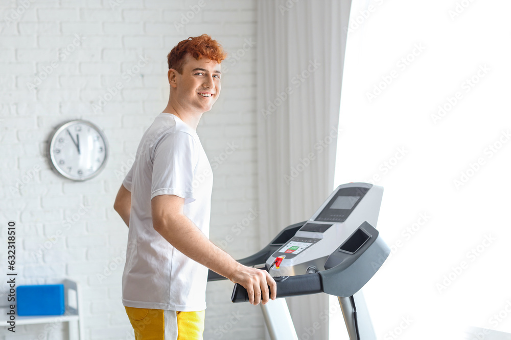 Young redhead man training on treadmill in gym