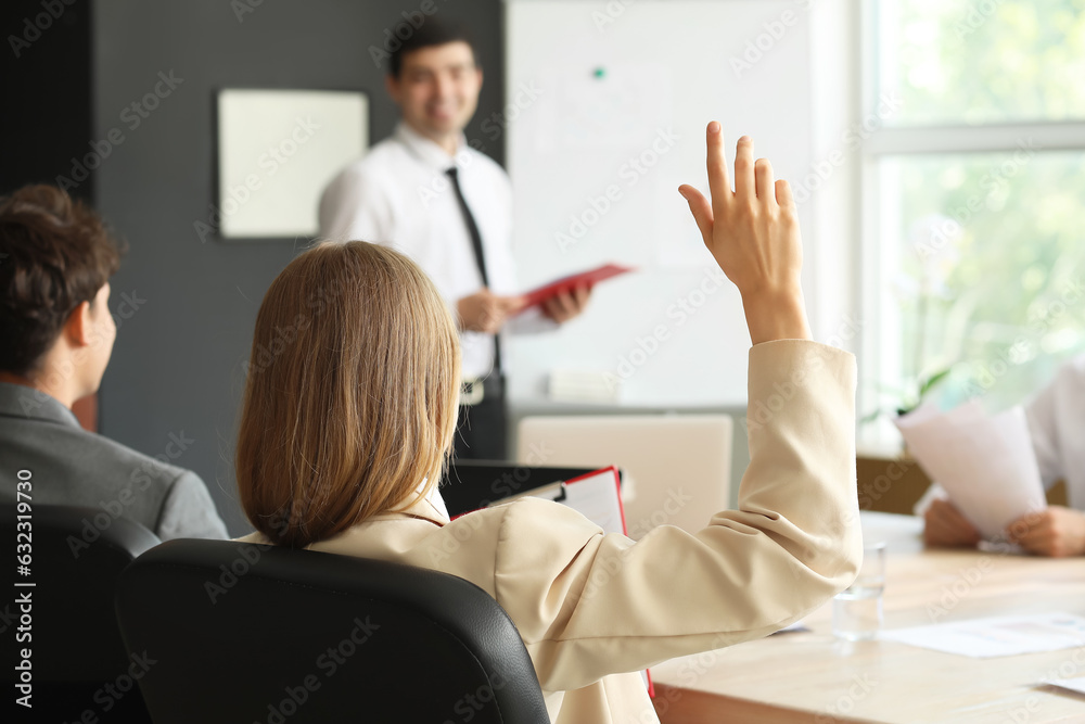 Female business consultant raising hand during presentation in office, back view