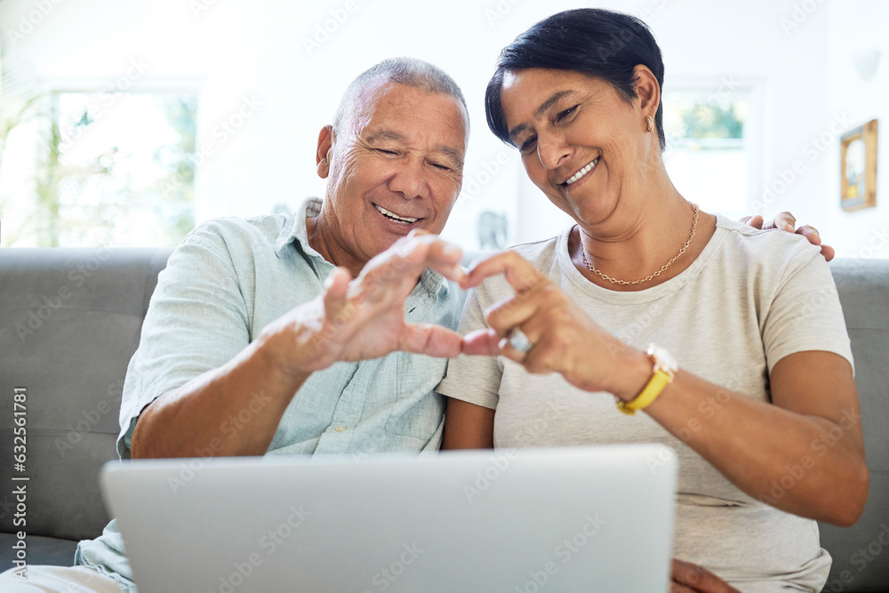 Mature couple, heart hands and laptop on home sofa for video call, streaming and internet. A happy m