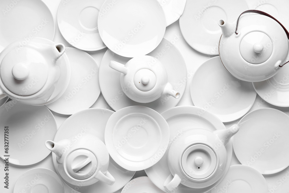 Composition with different teapots and plates on light background