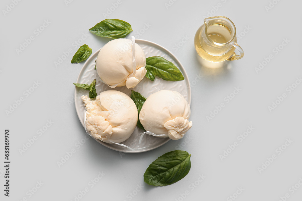 Plate of tasty Burrata cheese with basil and oil on white background
