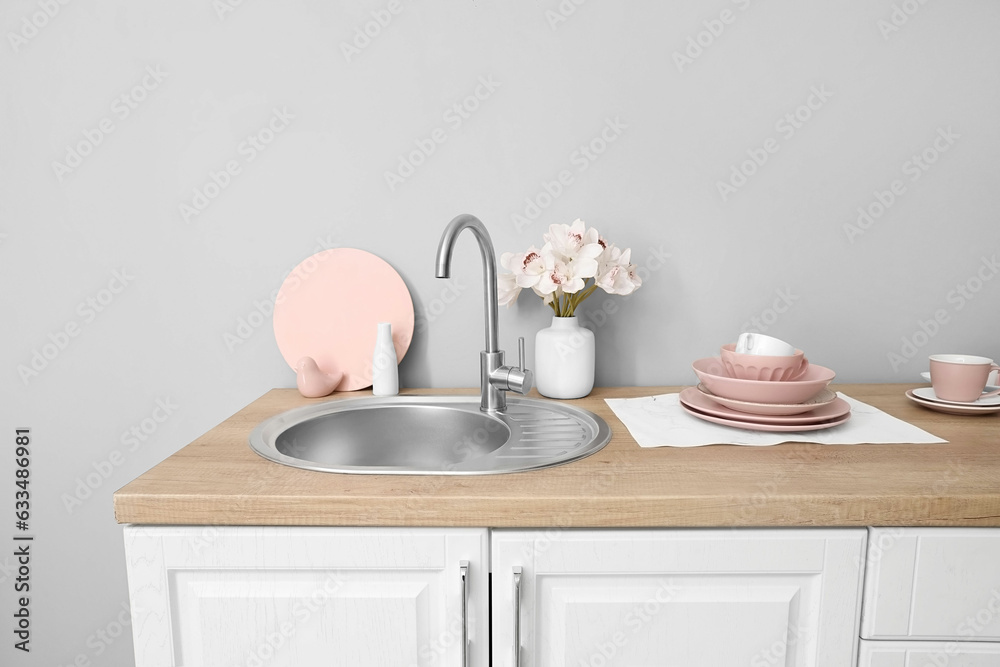 Kitchen counter with clean dishes, sink and orchid flowers