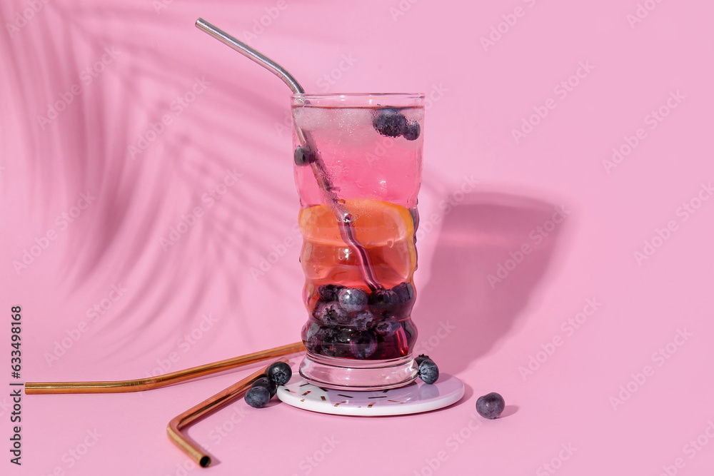Glass of fresh blueberry lemonade on pink background
