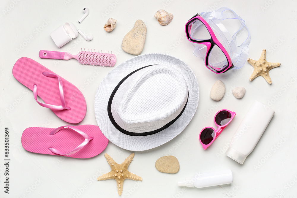 Composition with different beach accessories, earphones and hair brush on light background