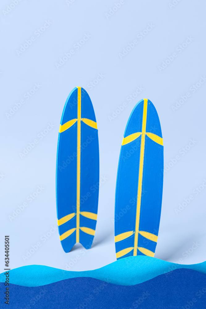 Creative composition with paper waves and mini surfboards on blue background