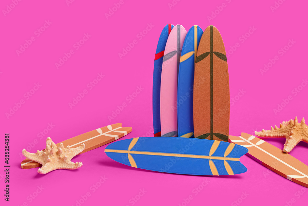 Different mini surfboards and starfishes on pink background