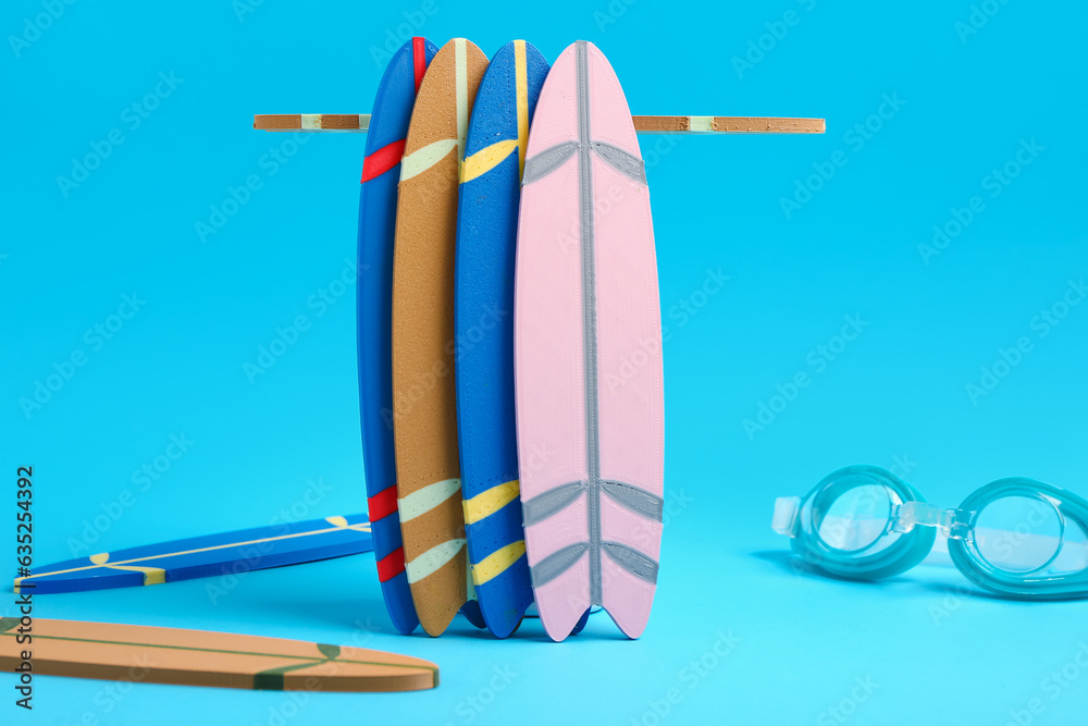 Different mini surfboards and goggles on blue background