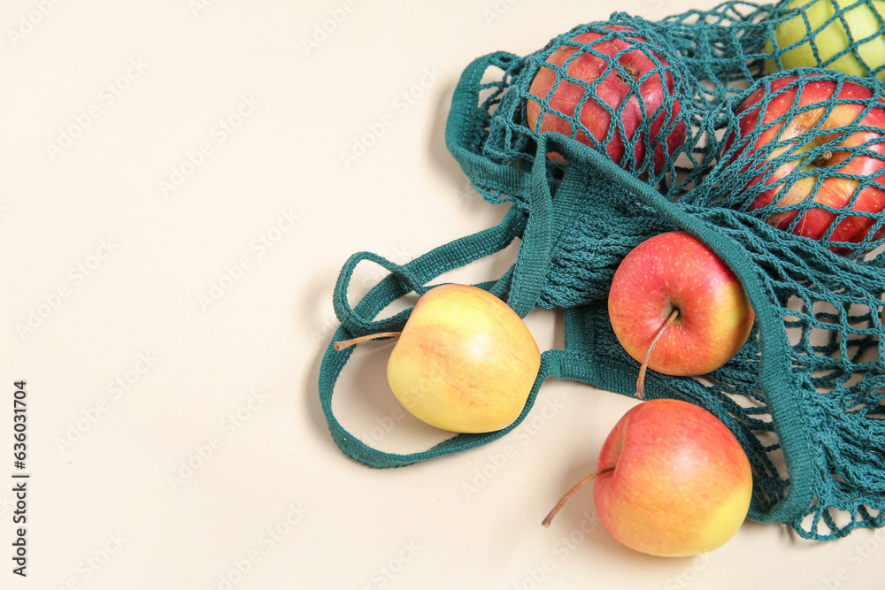 Mesh bag with fresh apples on beige background, closeup