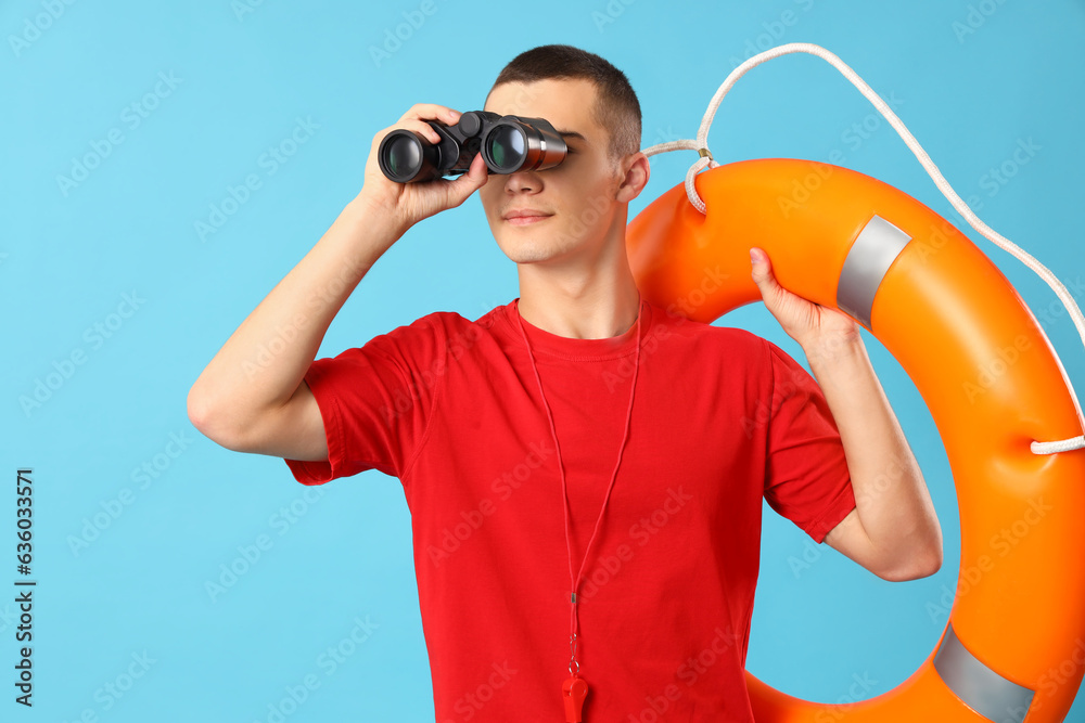 Male lifeguard with binoculars and ring buoy on blue background