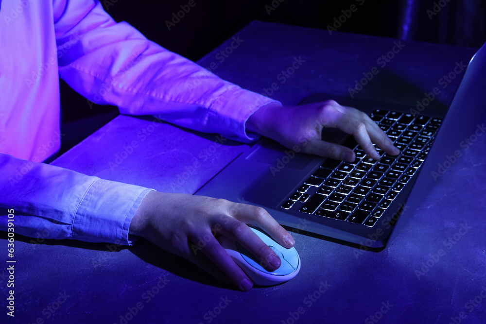 Female programmer working with laptop keyboard at night in office, closeup