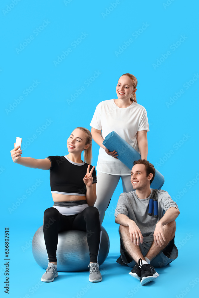 Sporty young people taking selfie on blue background