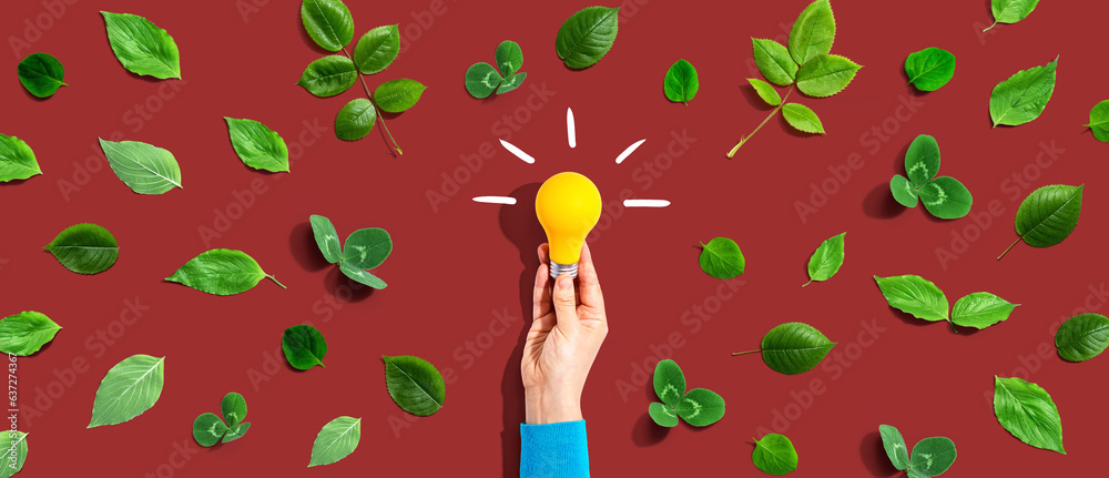 Person holding a light bulb with green leaves