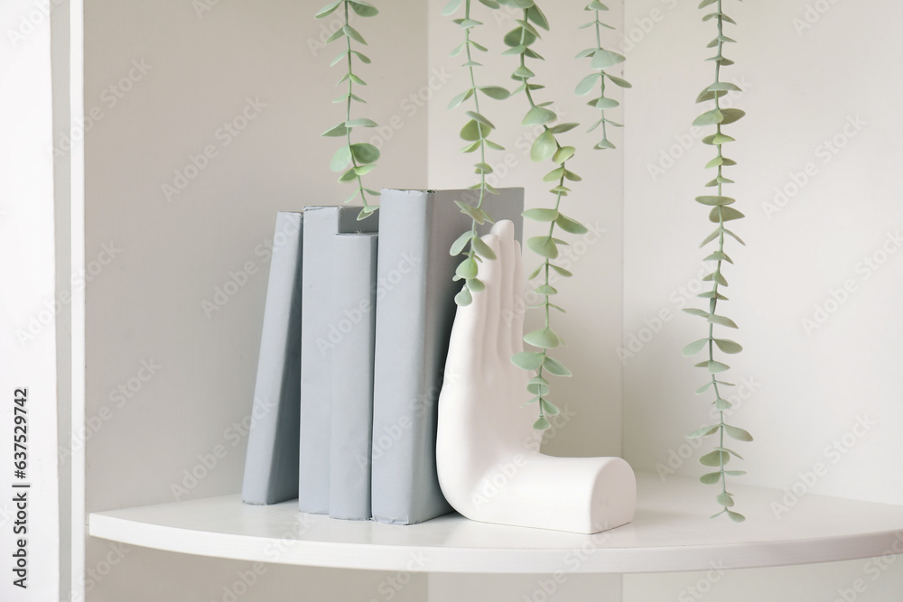 White shelving unit with stylish holder for books and houseplant