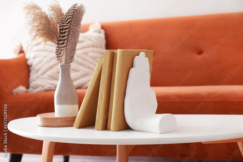 Stylish holder for books with vase on table in room