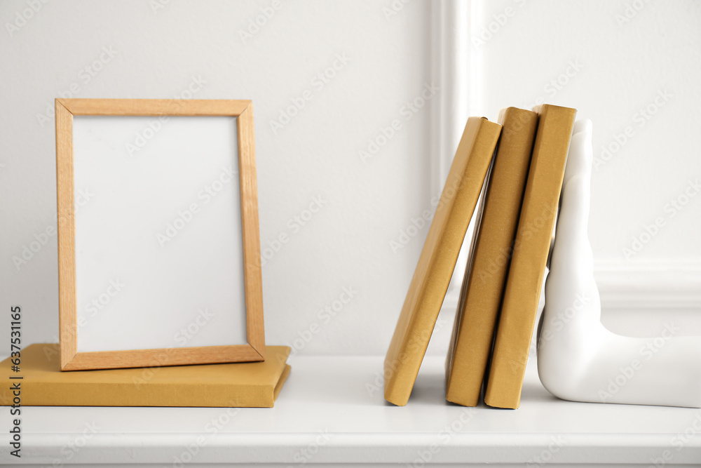 Stylish holder for books with empty frame on commode in room