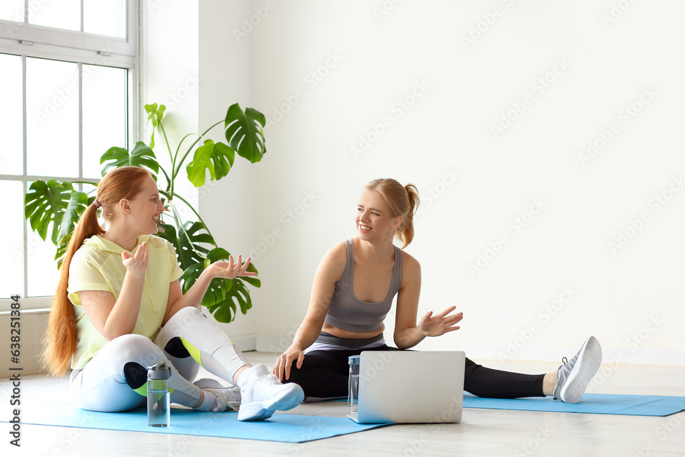 Sporty young women with laptop in gym
