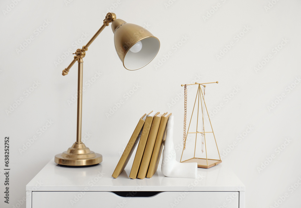 Stylish holder for books with lamp on commode in room