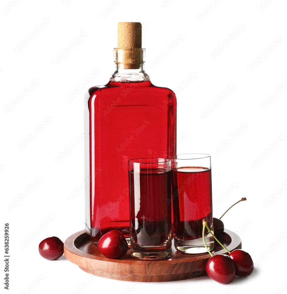 Glasses and bottle of sweet cherry liqueur with berries on white background