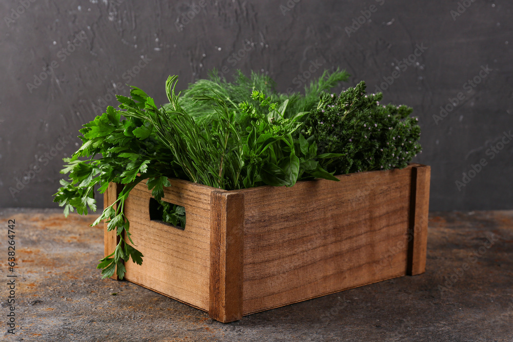 Wooden box with fresh herbs on table against dark background