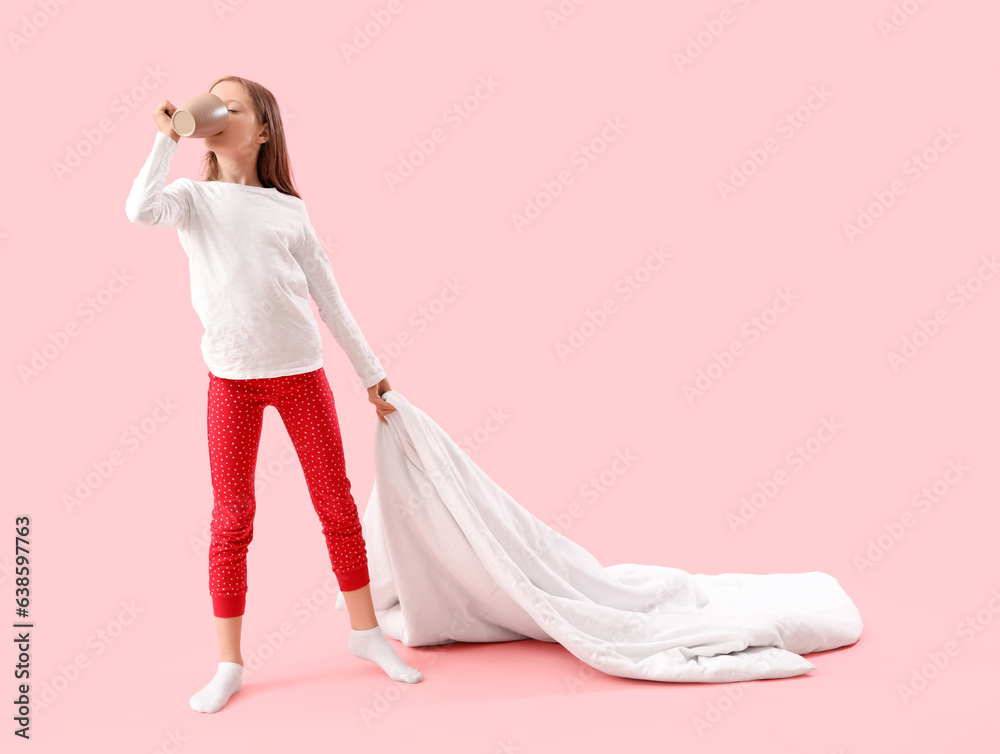 Little girl with blanket drinking milk on pink background