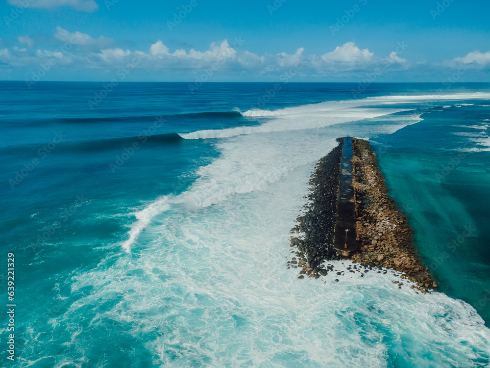 Perfect waves with barrels and breakwater in ocean. Aerial view