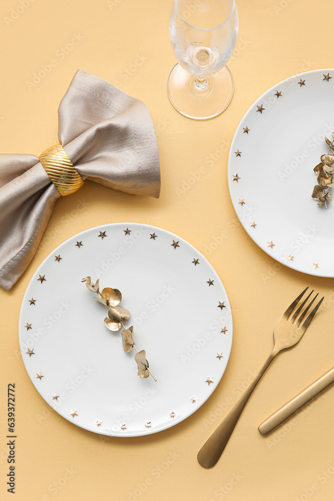 Elegant table setting with golden cutlery and leaves on yellow table
