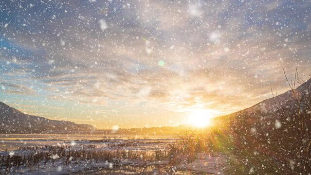 Beautiful winter landscape of mountain lake at sunset. Snowflakes falling in slow motion. Winter background.