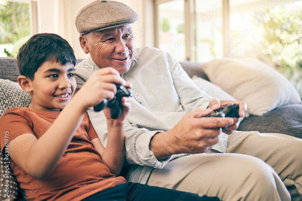 Family, fun and a boy gaming with his grandfather on a sofa in the living room of their home during 