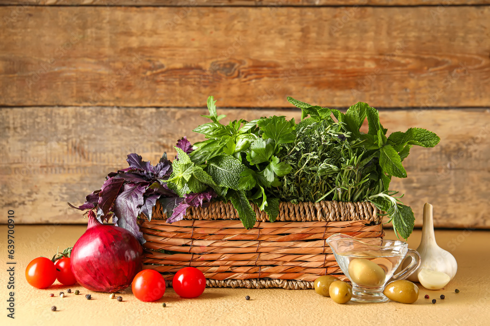 Wicker basket with fresh herbs and vegetables on table against wooden background