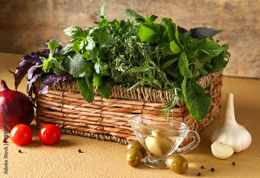 Wicker basket with fresh herbs and vegetables on table against wooden background